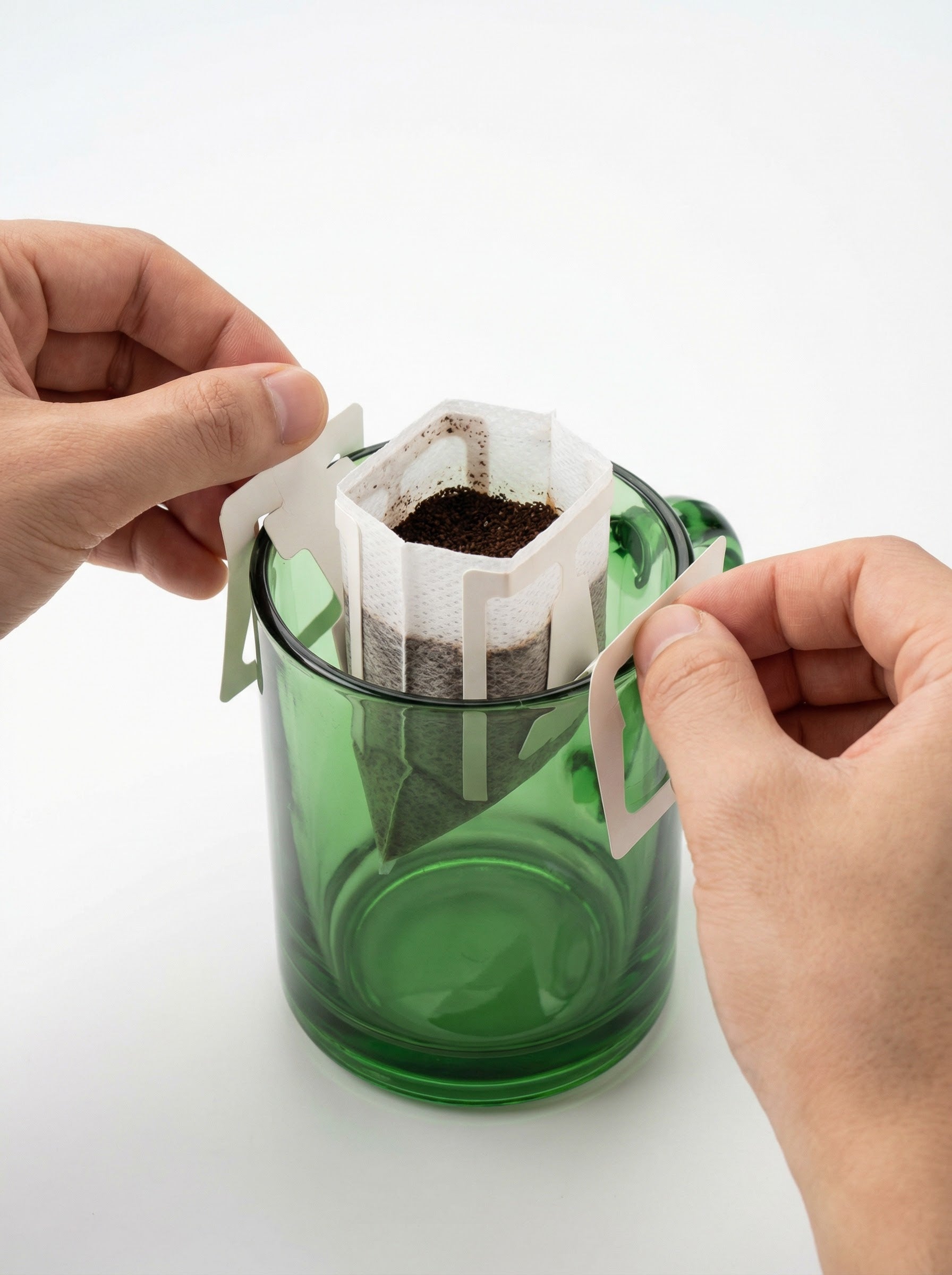 A KNDZ drip bag coffee filter hanging on the rim of a mug