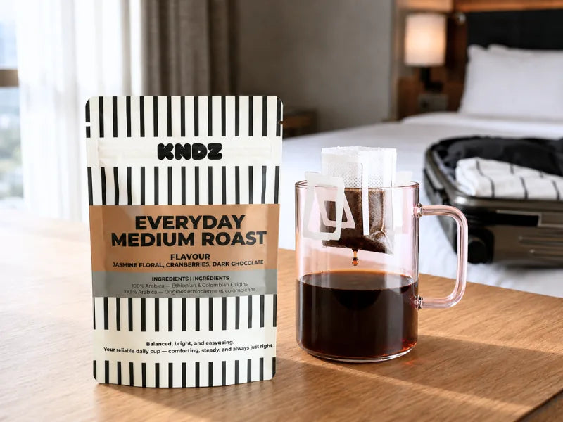A sealed KNDZ Everyday Medium Roast coffee pouch beside a freshly brewed cup